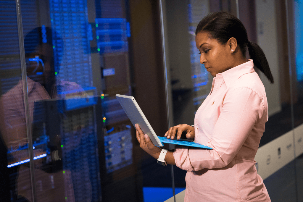 Professional using a laptop beside equipment racks in a data center